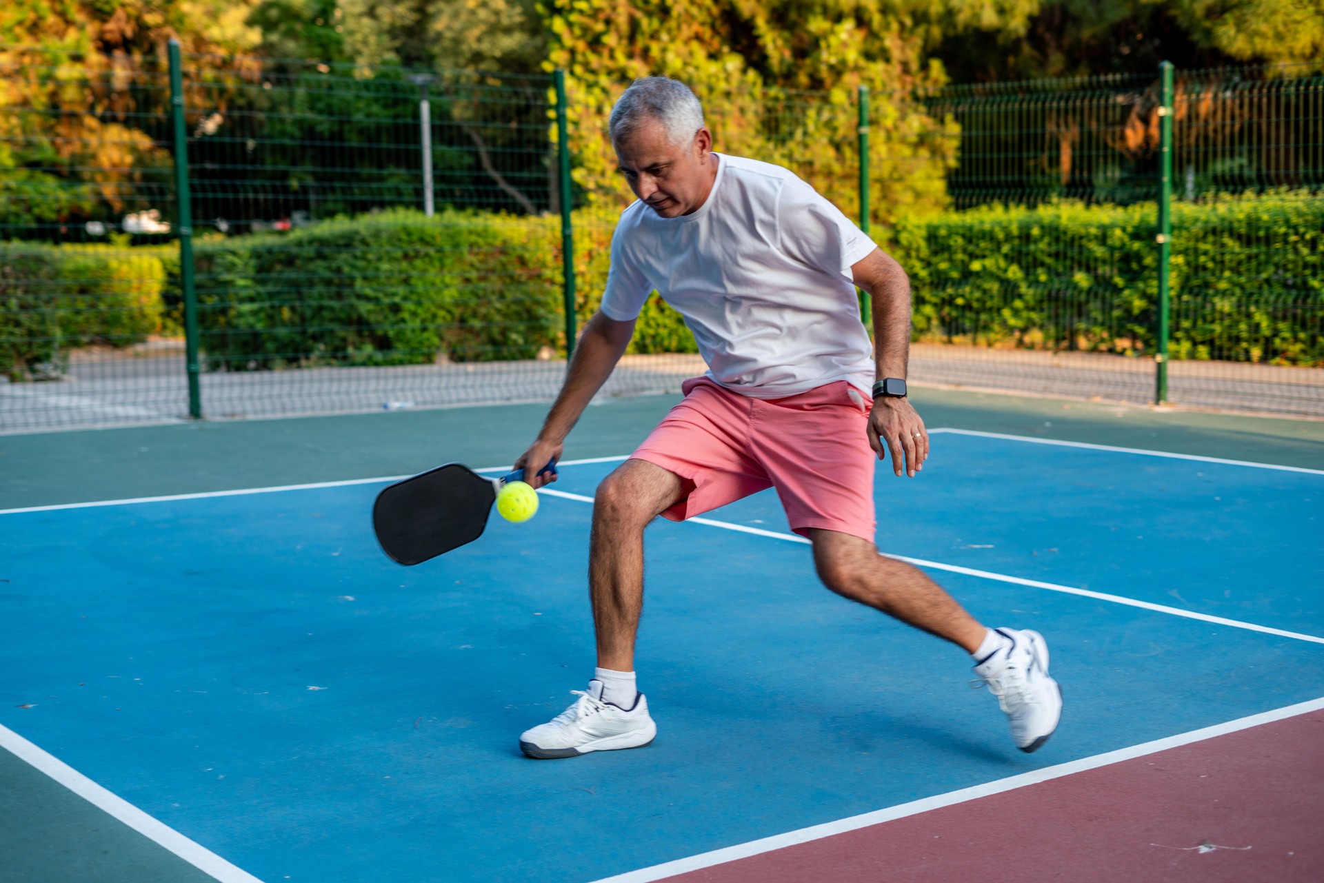 senior pickleball player is shooting forehand with motion blur horizontal sport still